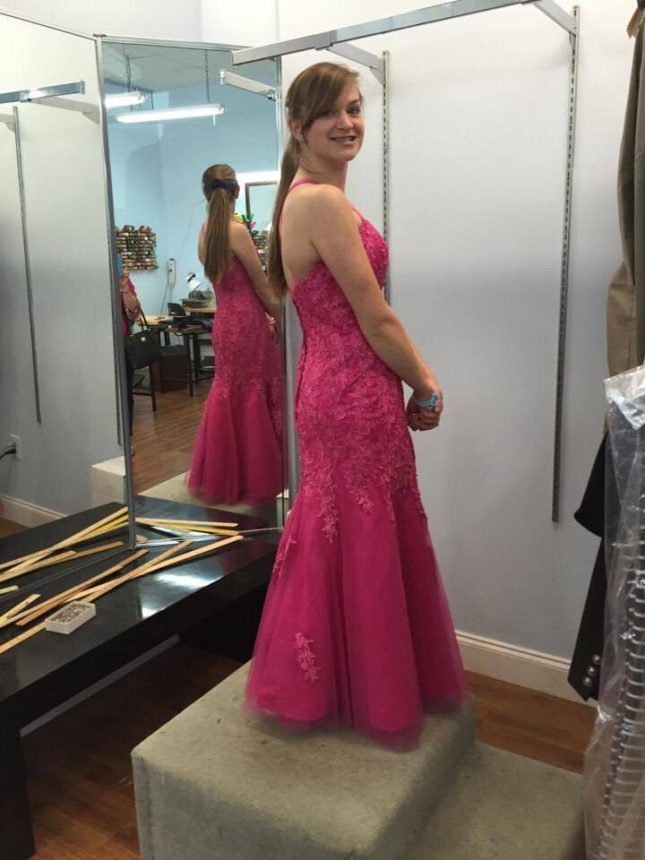 A customer trying on a fitted formal gown in the shop