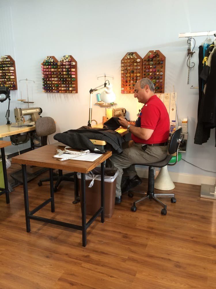 Tailor sewing at a workstation inside Nader's Alterations